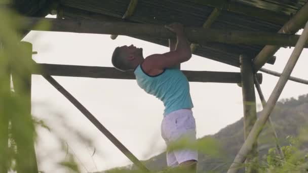 El entrenamiento del hombre fuerte tira para arriba en barra transversal de madera mientras que entrena al aire libre. Fitness haciendo pull ups ejercicio en barra horizontal en el gimnasio al aire libre. Concepto de entrenamiento fitness . — Vídeo de stock