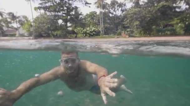 Un touriste plonge sous l'eau et nage masqué sur une plage tropicale en profitant de ses vacances. Concept de vacances tropicales . — Video