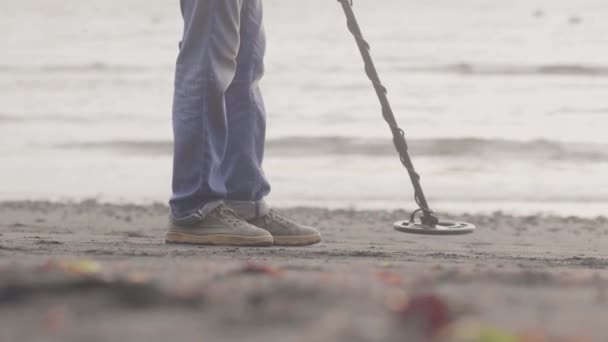 Człowiek pracuje na plaży gospodarstwa wykrywacz metali znalezienie metalu w piasku na wybrzeżu na wschód słońca. — Wideo stockowe