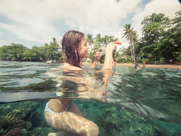 Mujer sonriente en mar transparente sosteniendo máscara de snorkel y vista de la línea de flotación del tubo. Mujer alegre en bikini con máscara de buceo y tubo para snorkel de mar. Isla Apo, Filipinas . —  Fotos de Stock