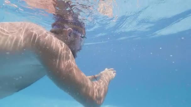 Joven en cámara lenta con gafas nadando bajo el agua piscina al aire libre en el hotel resort. Línea de agua masculina nadador en piscina al aire libre del hotel de verano . — Vídeos de Stock