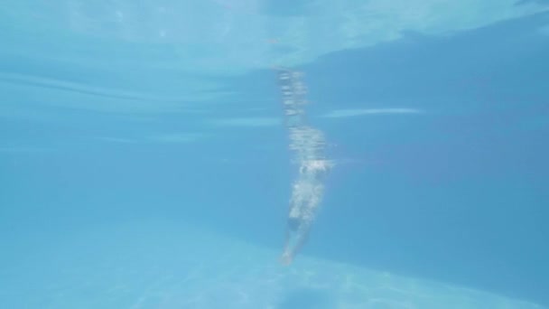 Wasserlinie Blick Mann Schwimmer Tauchen in Schwimmbad im Resort-Hotel. Zeitlupe. Junger Mann springt in schwimmendes Freibad und schwimmt unter Wasser. — Stockvideo