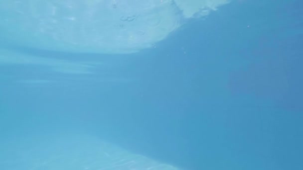 Joven buceando en agua azul en la piscina en cámara lenta. Vista submarina nadador macho saltando en agua transparente en piscina flotante . — Vídeos de Stock