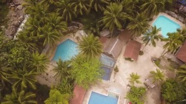 Tropikal resort otelde havadan görünümü mavi yüzme havuzu. Açık yüzme havuzu ve palmiye ağaçları arka plan ile Drone görünümü turistik otel.