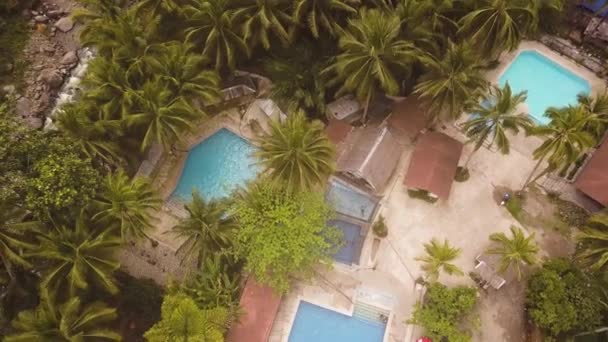 Aerial view blue swimming pool in tropical resort hotel. Drone view tourist hotel with outdoor swimming pool and palm trees background.