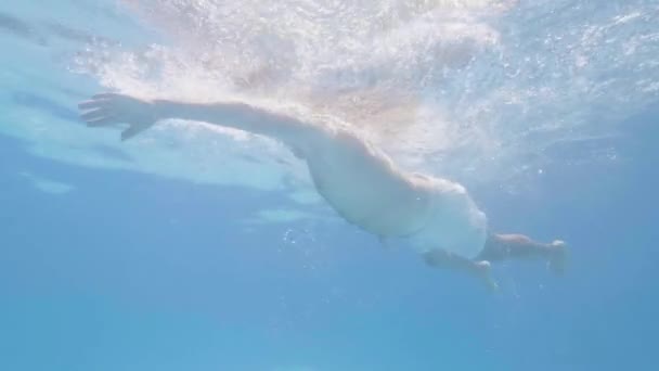 Nageur mâle flottant sous la piscine d'eau bleue. Vue sous-marine homme adulte nageant dans la piscine flottante. Sport nautique. Activité principale . — Video