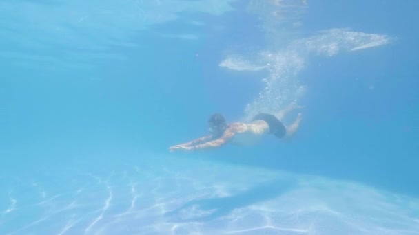 运动员男子在游泳池水下的蓝水中跳跃。男子游泳在护目镜潜水和游泳在清水漂浮池. — 图库视频影像