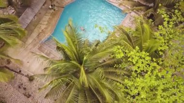 Tropik otelde mavi su yüzen havuzda yüzen Drone görünümü adam. Tropikal doğa arka plan üzerinde resort otelde hava manzara yaz bungalov ve yüzme havuzu.
