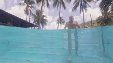 Olgun adam tatil oteli sualtı görünümünde merdivenle su yüzme havuzuna giriyor. Turist otel su hattı görünümünde açık yüzme yetişkin adam.
