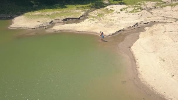 Joven hombre y mujer la captura de peces en la caña de pescar hecha a mano en el agua del lago en la selva tropical y el paisaje de montaña. Vista aérea joven pareja pesca en lago tropical en viaje de verano . — Vídeo de stock