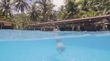 Waterline görünümü adam yüzücü resort otelde yüzme havuzunun mavi su dalış. Turist otelde sualtı yüzen havuz yüzme maskesi genç adam yüz.
