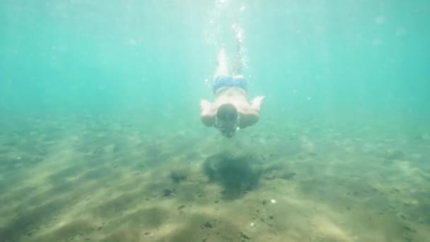 Joyeux jeune homme voyageur plonge sous l'eau dans un masque dans l'océan en vacances . — Video