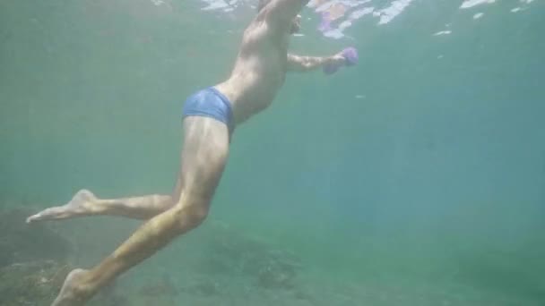 Athletic man freediver is training with dumbbells underwater in ocean, side view. — Stock Video