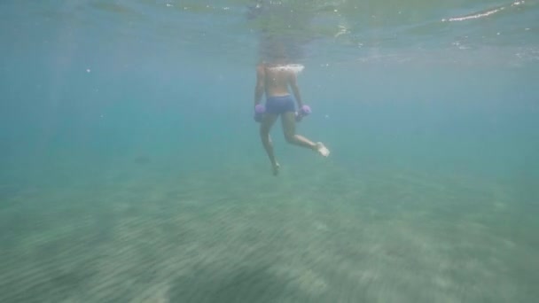 Desportista atlético está fazendo exercícios com halteres subaquáticos no oceano . — Vídeo de Stock