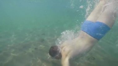 Adam mavi berrak suda kum dibinde okyanusta yüzüyor ve dalış.