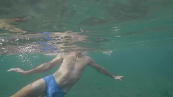 Glücklicher Touristenmann schwimmt und taucht im Urlaub auf tropischer Insel in Ozean. — Stockvideo