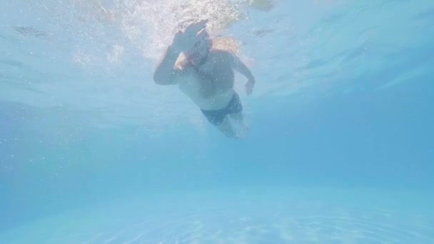 ゴーグルの男の肖像画は、スイミングプールで水中の息を保持して泳いでいます. — ストック動画