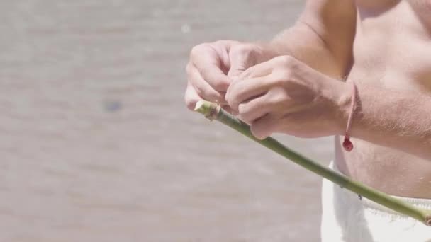 Man binder en fiskelina till kanten av bambu pinne, handgjorda fising Rod, händer närbild — Stockvideo