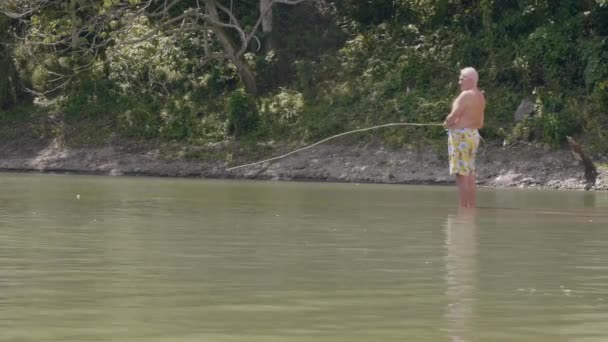 Hombre mayor está pescando en el lago en el fondo de las montañas en la isla de Tropcal . — Vídeo de stock