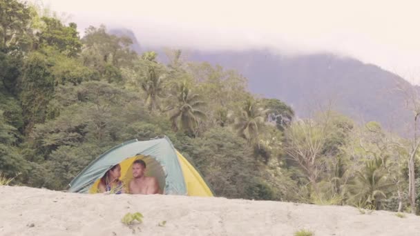 Пара в палатке в тропических лесах на фоне гор . — стоковое видео