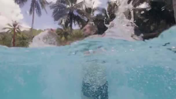 Hombre alegre salpicaduras de agua en la piscina al aire libre en el hotel resort. Línea de flotación vista hombre feliz divertirse en la piscina en las vacaciones de verano . — Vídeo de stock