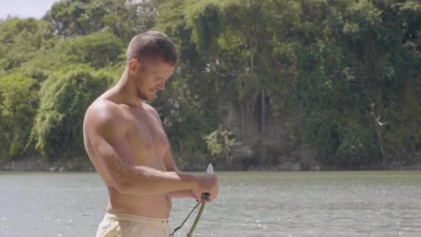 Junger Mann schneidet Bambusstab, um in wilder Natur eine Angelrute zu bauen. — Stockvideo