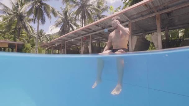 Jovem turista está a aproveitar o sol sentado perto da piscina na ilha tropical . — Vídeo de Stock