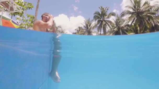 L'homme plonge dans la piscine et nage libre en plein air sur une île tropicale . — Video