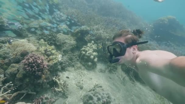 Man is snorkeling in ocean among coral reefs shooting himself on action camera. — Stock Video