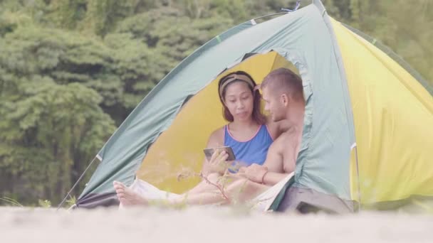 Man and woman in tent are watching something in mobile phone and discussing. — Stock Video