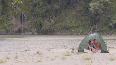 Erkek ve kadın küçük şelale ile güzel tropikal göl üzerinde çadırda dinleniyor.