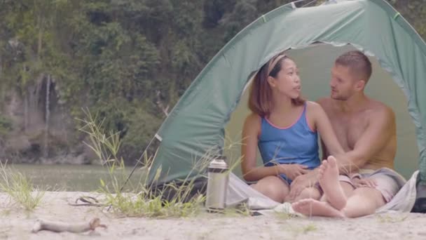 Young couple sitting in tent in wonderful place. They are talking and laughing. — Stock Video