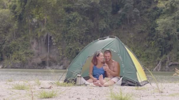 Casal feliz em acampar em lugar bonito. Eles estão bebendo chá na tenda . — Vídeo de Stock