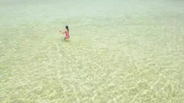 Letecký pohled na dívčí procházky v oceánu, pohled na kameru a úsměvy na ostrově laguny. — Stock video