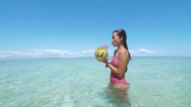 Seksi bir mayo Asyalı turist sıcak bir yaz gününde taze hindistan cevizi suyu içmek.