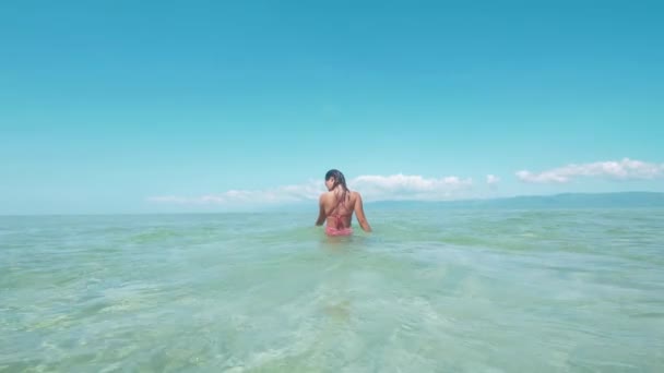 Вид сзади, женщина купается в чистой океанской воде в солнечный день на Филиппинах , — стоковое видео