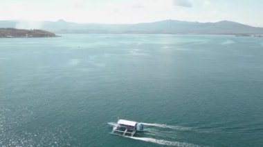 Mavi okyanusta seyreden bir turist teknesinin havadan görünümü.