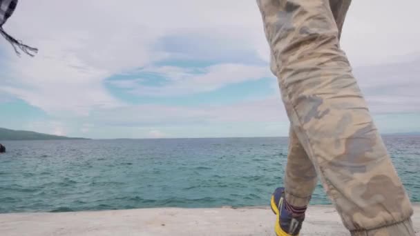 Coppia interrazziale si tiene per mano, camminando verso il mare guardando il paesaggio marino . — Video Stock