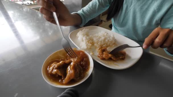 Vista parcial de una joven comiendo carne de cerdo y arroz sobre la mesa . — Vídeos de Stock