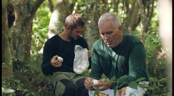 Zwei Bergsteiger essen gekochte Eier im Dschungel. — Stockvideo