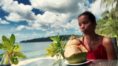 Güzel Asyalı kız sıcak güneşli bir günde taze hindistan cevizi suyu içme keyfini çıkarın