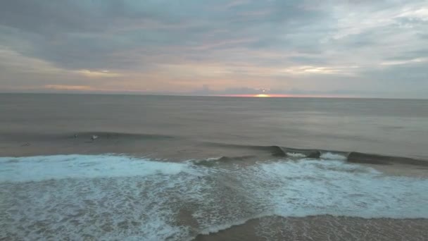 日の出とサーファーが早朝にサーフィンを楽しむ美しい海景. — ストック動画