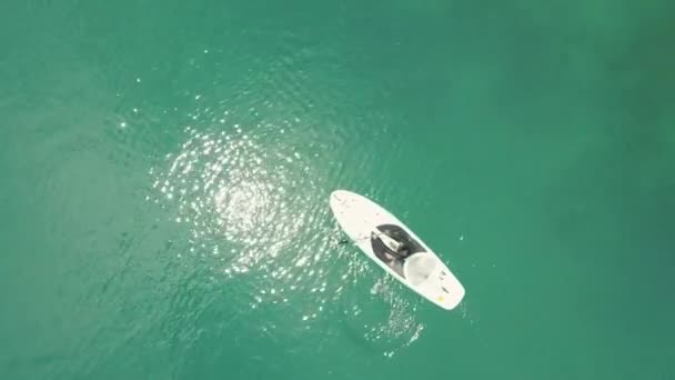 Flygfoto av ung turist paddlebording i lagunen med glimrande vatten. — Stockvideo