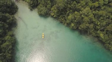 Yeşil orman ve mavi lagünün havadan görünümü ve su üzerinde turist kano.