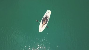 Havadan çekim: mavi denizde bir paddleboard üzerinde yatan seksi brunnette geri görünümü.