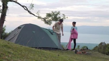 Kadın ve erkek dağda güzel bir kamp yerinde bir çadır kurma.