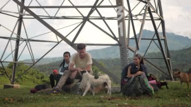 Dağdaki bir kulenin altındaki kayalıklarda oturan kampçılar, köpeklerle oynuyorlar..
