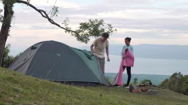 Homme et femme installant une tente dans un bel endroit de camping dans la montagne . — Video
