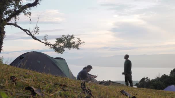 Drei Freunde entspannen auf einem Campingplatz in den Bergen mit malerischer Landschaft. — Stockvideo