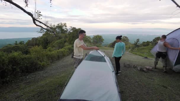 Acampantes colocando tendas mais thier no local de acampamento na colina com vista incrível — Vídeo de Stock